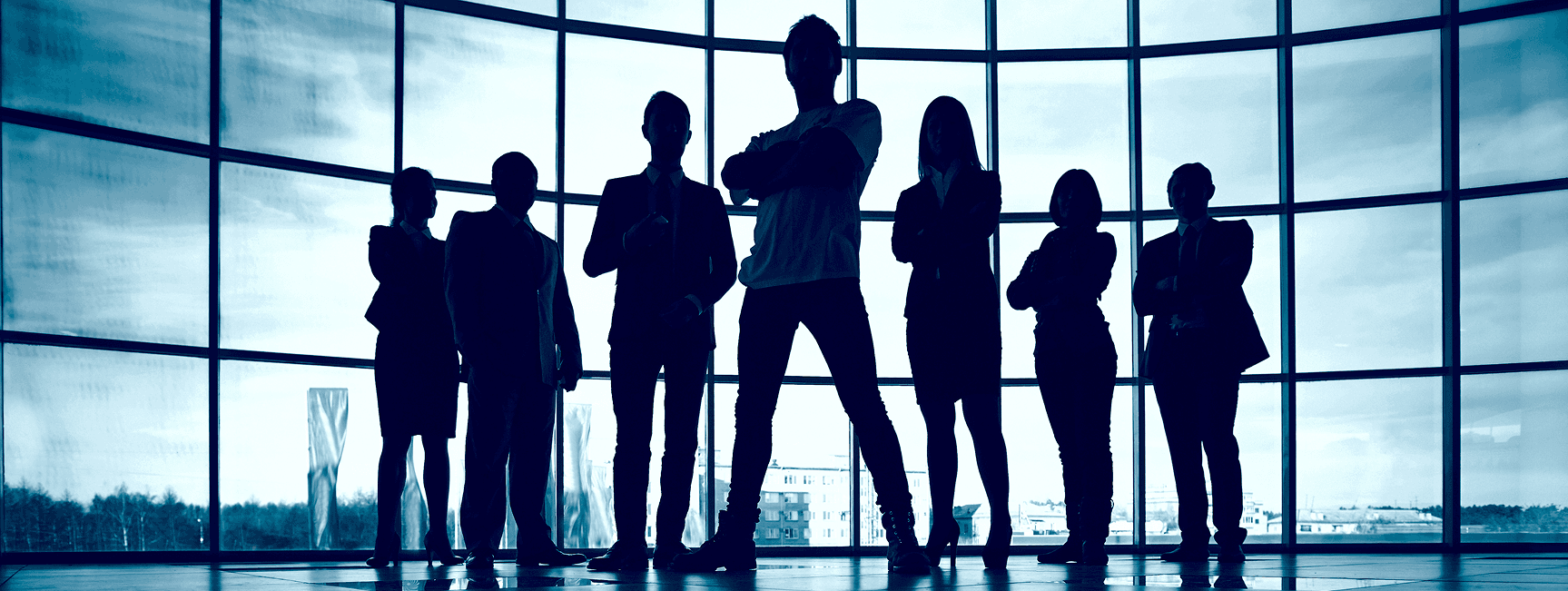 Silhouettes of professionals in front of a glass facade